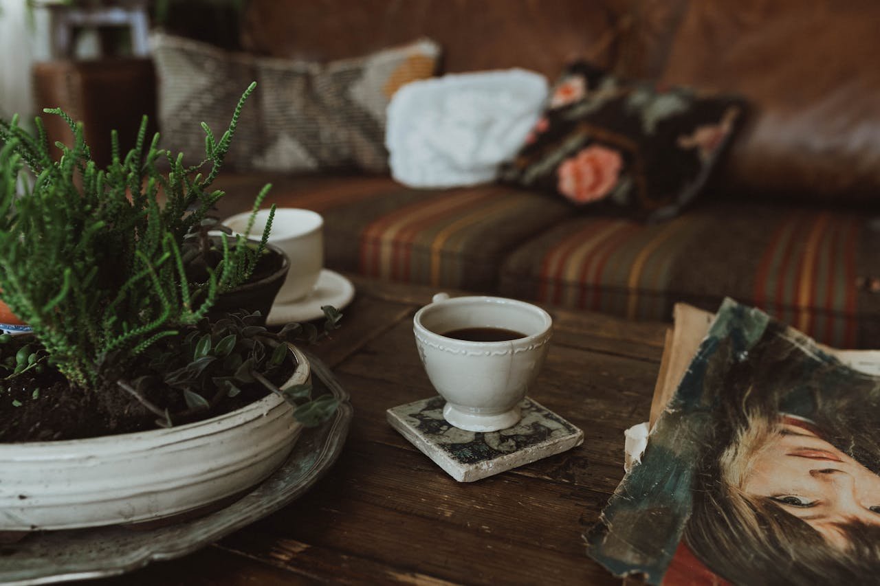 A cozy indoor scene with a rustic table, potted plants, and a cup of tea, creating a warm atmosphere.