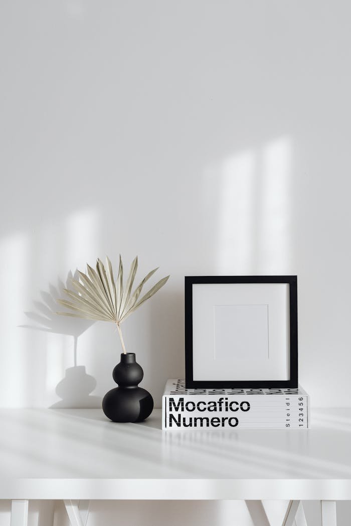 Elegant minimalist interior featuring a black frame, modern vase, and decor books.
